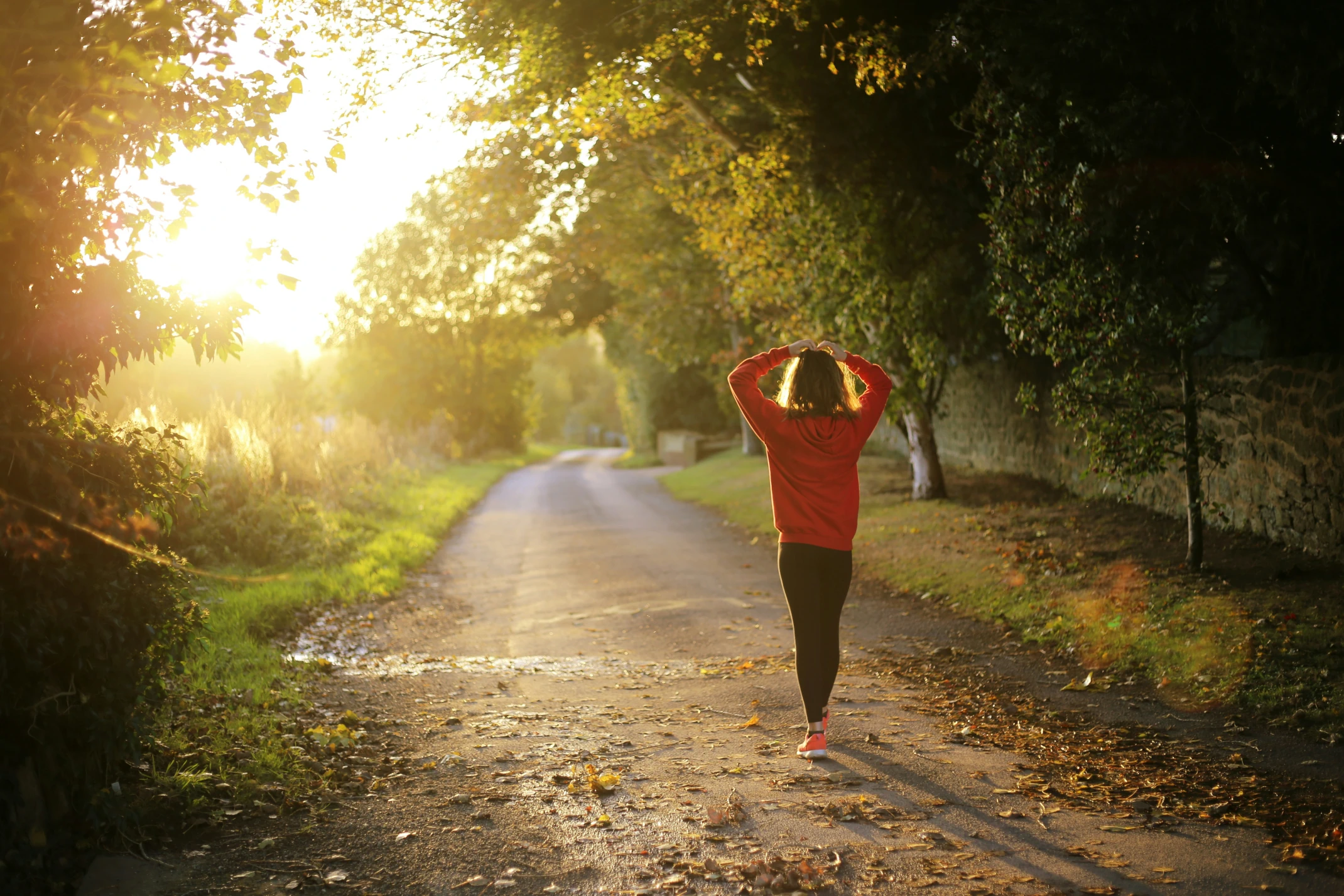 A woman walking on a path into the sunlight