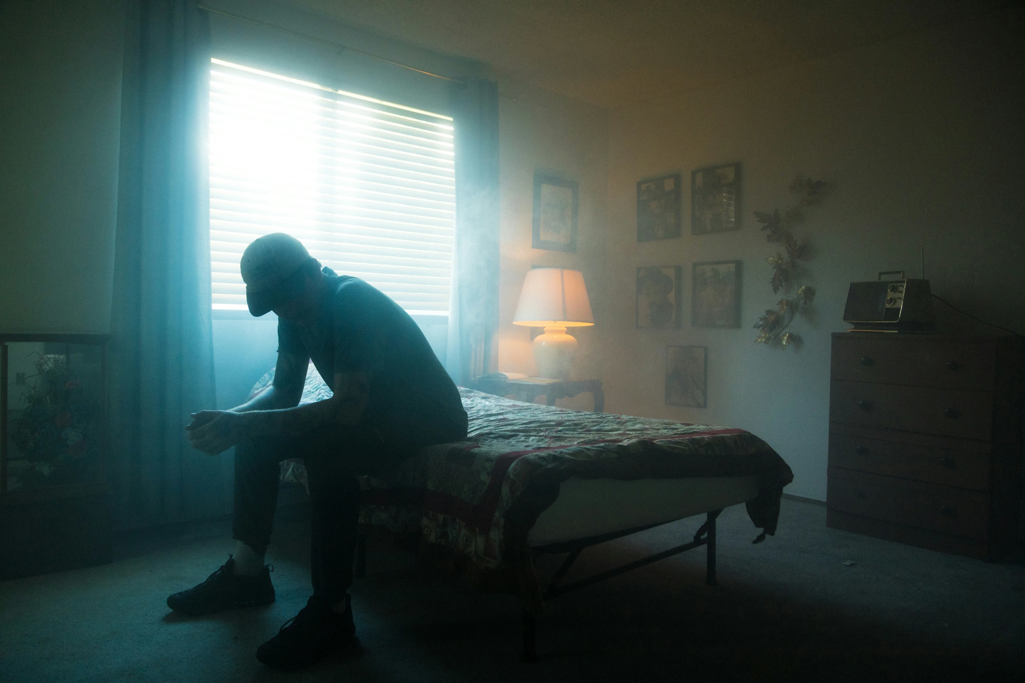 A man sitting on a bed in a smokey room