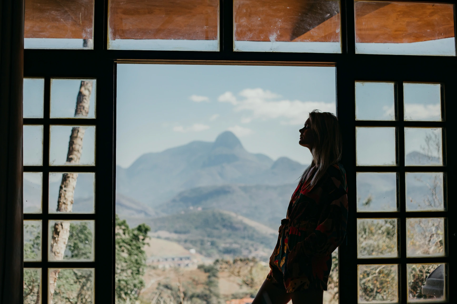 A woman leaning in a doorway with mountain in the background